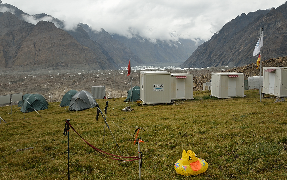 20130804-079-Trek.jpg - One can almost guess the -- now empty -- Merzbacher lake. In the foreground the mascot of four young austrian trekkers who came over the Tuz pass and the cabins of the Geo Center of Potsdam